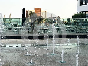 A small singing fountain in the open air, on the street. Drops of water, jets of water frozen in the air in flight