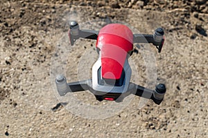 Small sized red drone with high resolution camera hovering in air for aerial photography