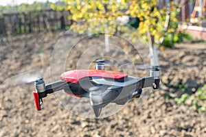 Small sized red drone with high resolution camera hovering in air for aerial photography