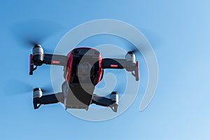 Small sized red drone with high resolution camera hovering in air for aerial photography