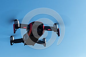 Small sized red drone with high resolution camera hovering in air for aerial photography