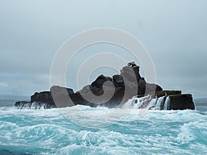 Small skerry in the middle of the sea under a cloudy sky