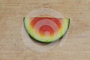 Small slice of seedless watermelon, centered on a worn bamboo cutting board