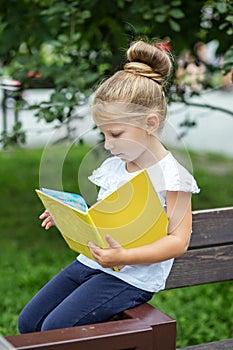 A small smart child is reading an interesting book. The concept is back to school and upbringing