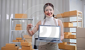 A small SME business owner stands holding a laptop with a white screen. Use a laptop to record small business