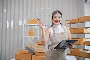 A small SME business owner writes inventory and shipping information on a clipboard in his home office. Small business