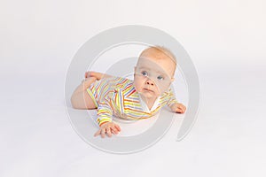 Small smiling baby girl 6 months old lies on a white isolated background in a bright bodysuit, space for text. A healthy happy