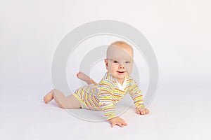 Small smiling baby girl 6 months old lies on a white isolated background in a bright bodysuit, space for text. A healthy happy