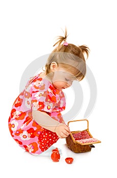 Small smiling baby in red dress with toy basket