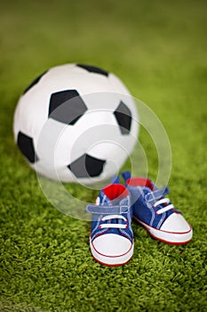 Small sneakers and a soccer ball. concept of expecting a boy