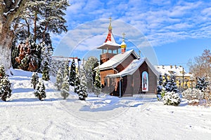 Small snow-covered wooden Orthodox chapel with domes in winter