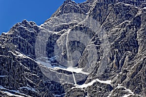 Small snow-slide at mountain massif by blue sky