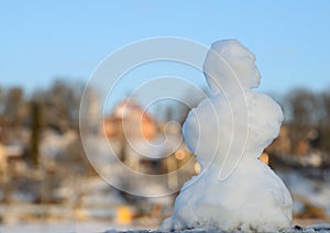 Small snowman at the Viljandi lake against Viljandi city and blue sky out of focus background. Shooted at golden hour. Viljandi, E