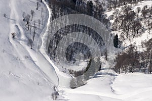 Small snowy road in mountain woods from above, Orobie