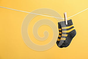 Small socks hanging on washing line against color background. Baby accessories