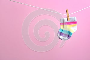 Small socks hanging on washing line against color background. Baby accessories