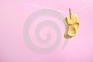 Small socks hanging on washing line against color background. Baby accessories