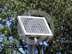 Small solar panel on pole with trees