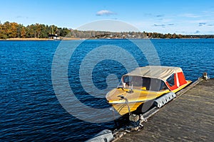 Small speed boat yellow colored boat is moored at wooden pier. Swedish coast in autumn. Beautiful colorful panoramic view of the