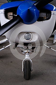 Small sport aircraft in hangar, front view of engine, propeller and nose wheel