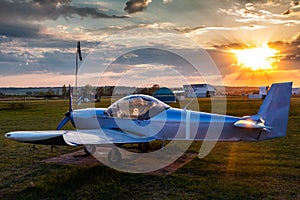 A small sports aircraft parked at the airfield at picturesque sunset