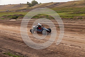 A small sports blurred buggy on a rally competition track during weekend training on a warm summer day