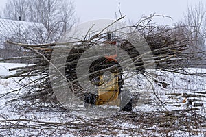Small stand-on mini skid steer with grapple full of wooden branches