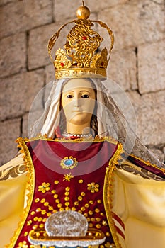 Small statue of the Virgin Mary with accessories and tunic in cherry and yellow on an altar