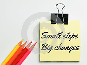 Small steps big changes written on yellow paper note with colorful pen.