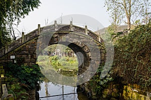 Small stone arch bridge over brook at sunny winter noon