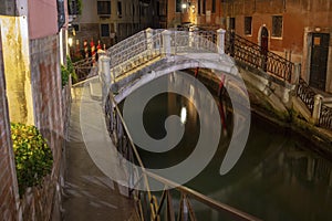 Small stone bridge spanning the Venetian canal by night