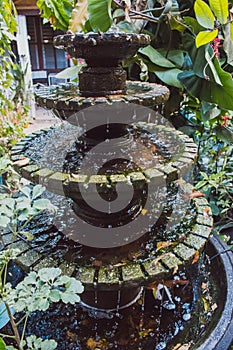Small stone fountain in tropical garden. Fountain in vase in asian backyard. Zen and peace concept.