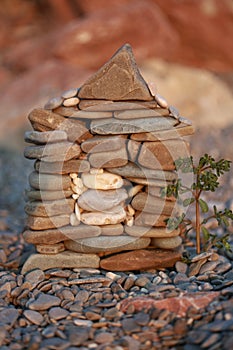 A small stone House construction with a tree in front of it on beach background