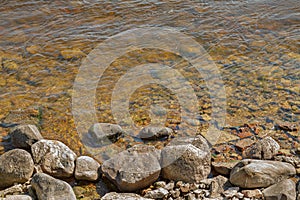 Small stones on the shore of a lake with clean water.