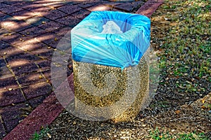 Small stones trash can with a blue garbage bag