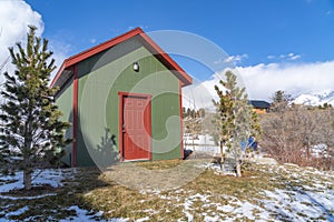 Small storage shed on grassy terrain with trees and powdery snow