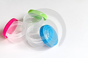 Small storage tubs, with brightly coloured lids on white background.