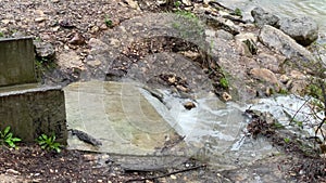 Small stream flowing along designated place into large river. Mountain waterway flowing down through mountainous terrain