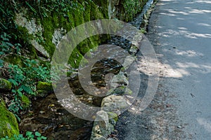 Small stream flowing beside paved rural road