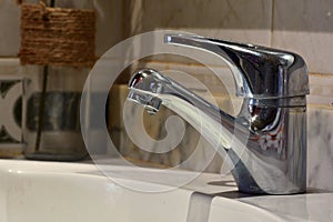 Small stream of water falling from a sink faucet photo