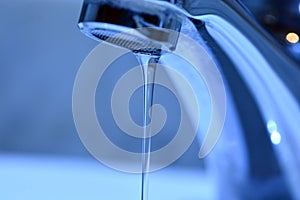 Small stream of water falling from a sink faucet photo