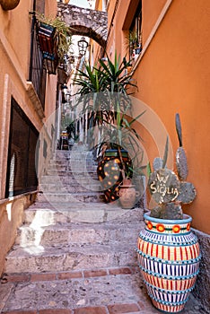 Small street of Taormina city and cactus with word SICILIA. Sicily, Italy