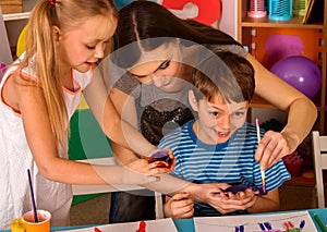 Small students finger painting in art school class.