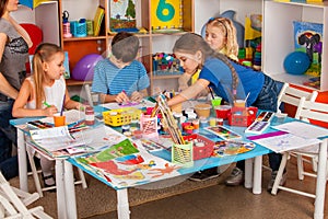 Small students girl and boy painting in art school class.