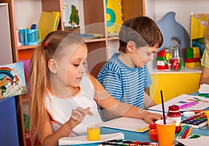 Small students girl and boy painting in art school class.