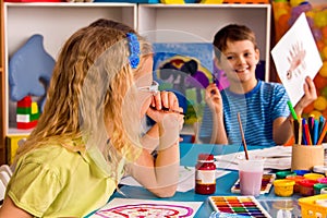 Small students girl and boy painting in art school class.