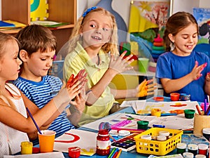 Small students girl finger painting in art school class.