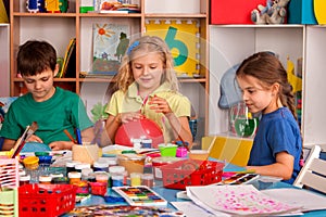 Small students girl finger painting in art school class.