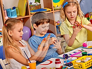 Small students girl finger painting in art school class.