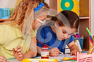 Small students girl painting in art school class.